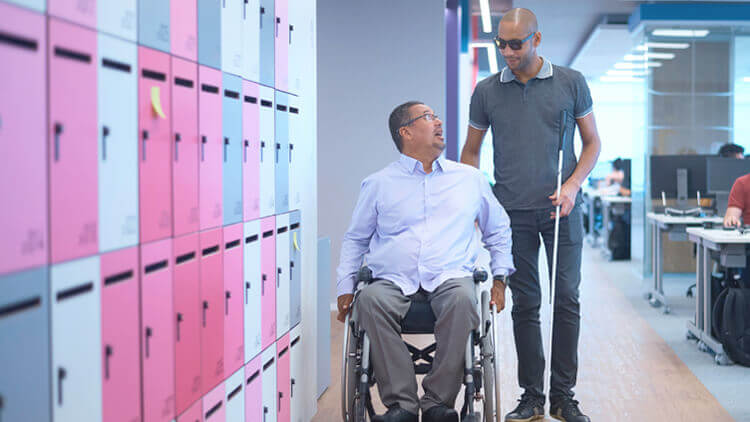 Two Experian employees in the office, one in a wheelchair and one with a visual impairment  