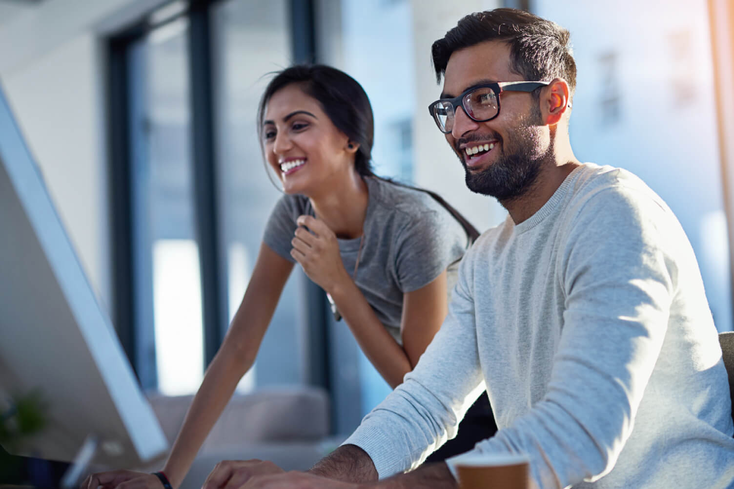 hombre y mujer sonriendo mirando computador