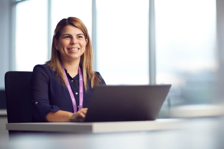 mujer sentada sonriendo mirando al frente con computador