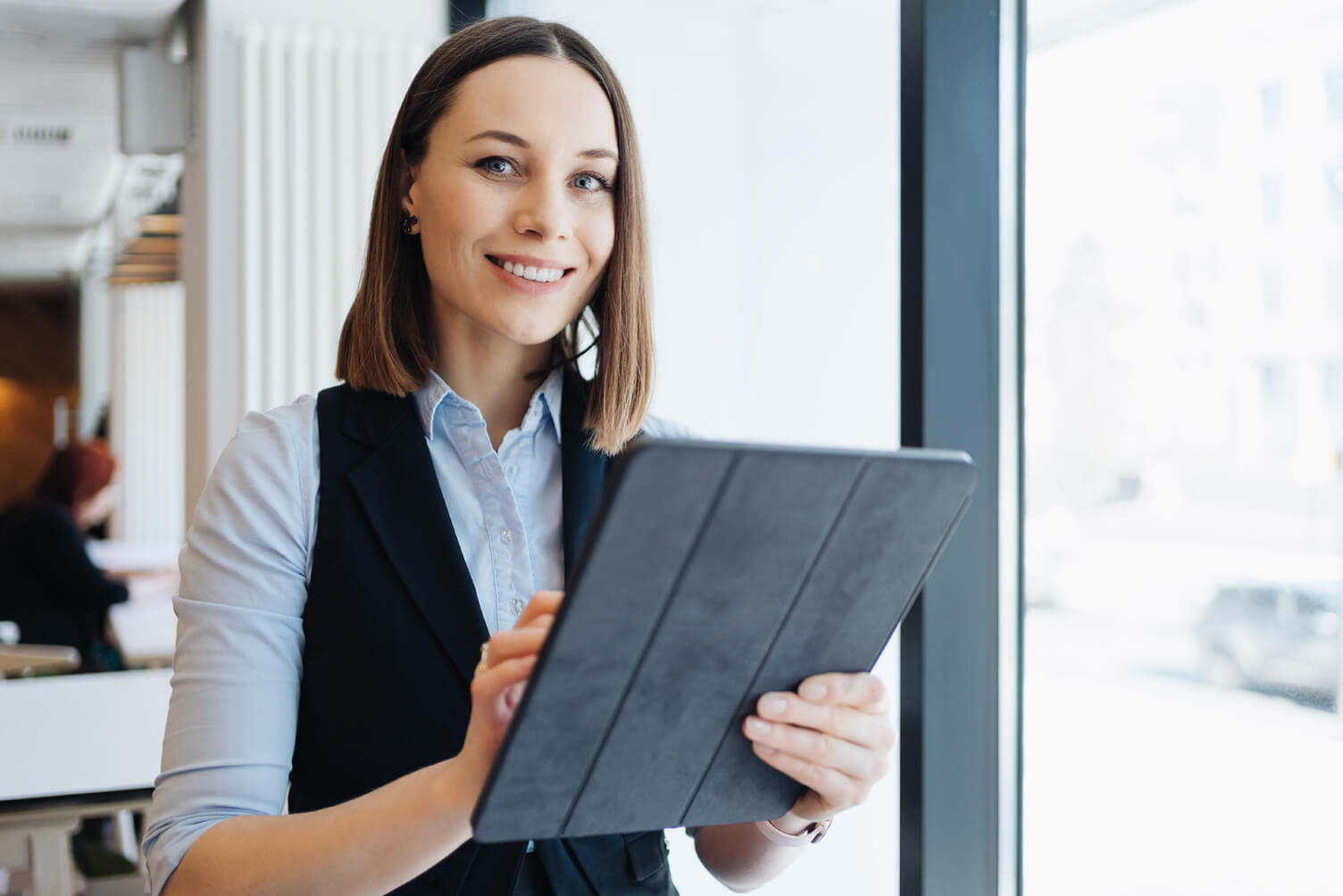 mujer sonriendo mirando al frente con tablet en la mano