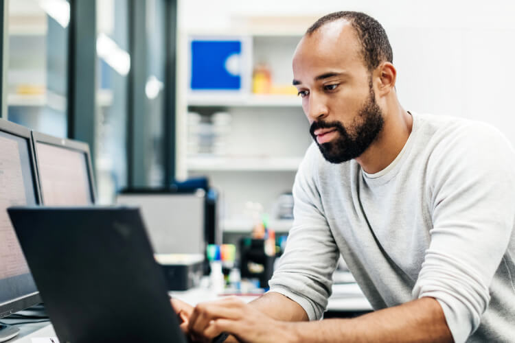 hombre mirando y escribiendo en un computador